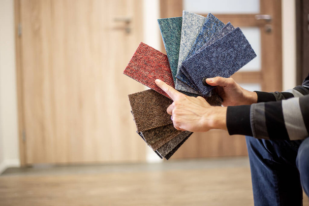 Hombre eligiendo el color de la alfombra rigt para su nuevo apartamento en el estudio de piso, suelos
 - Foto, imagen