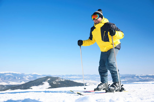 Young man skiing on hill, space for text. Winter vacation - Photo, image