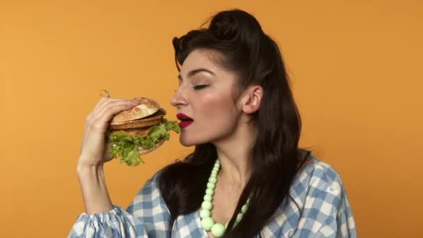Pin się kobieta uśmiecha i gryzie hamburgera z zamkniętymi oczami - Materiał filmowy, wideo