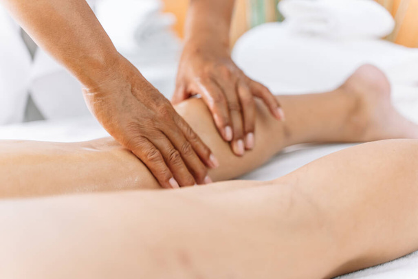Szczegóły rąk kobiety masującej nogi kobiety leżącej na leżance z białymi ręcznikami w centrum masażu - Zdjęcie, obraz