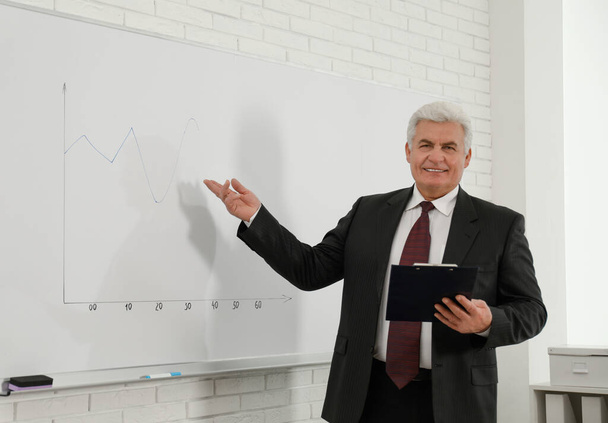 Senior business trainer near whiteboard in office - Photo, image