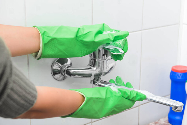 Janitor cleaning faucet in bathroom - Fotoğraf, Görsel