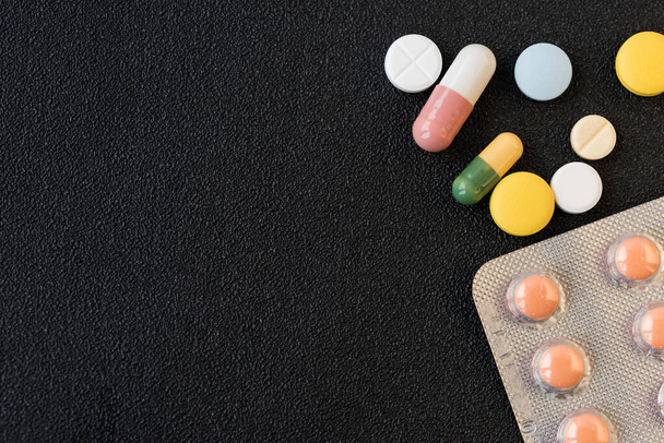 Stapel von Medikamenten Pillen Nahaufnahme auf schwarzem Hintergrund. Konzept des Gesundheitswesens. Kopierraum. - Foto, Bild