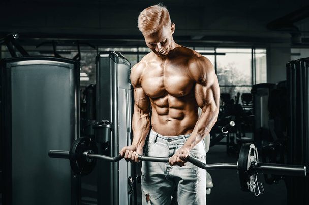 Bodybuilder handsome strong athletic rough man pumping up biceps muscles workout fitness and bodybuilding healthy concept background - muscular fitness men doing arms exercises in gym naked torso - 写真・画像