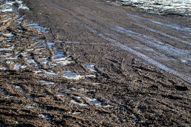 Грязная размытая грунтовая дорога со следами шин весной. Внедорожник. - Фото, изображение