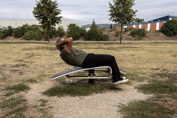 Side View középkorú férfi csinál Crunches hasi pad játszótér - Fotó, kép