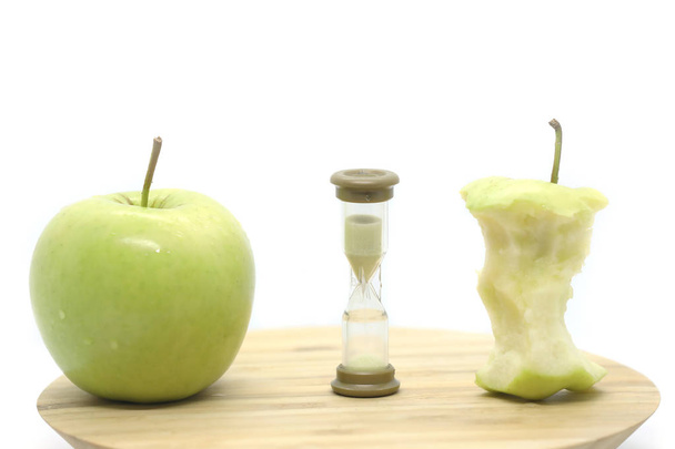 Manzana verde, vidrio de arena y núcleo de manzana en una placa de madera aislada sobre un fondo blanco
. - Foto, imagen
