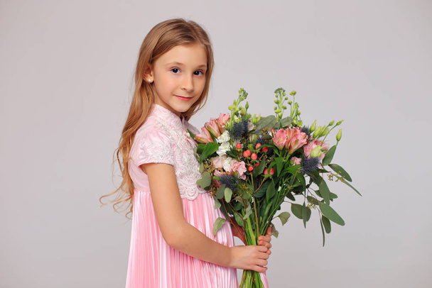 Cute little girl with flowers in her hands - Foto, Imagen