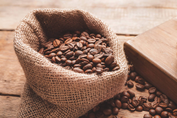 Bag with coffee beans on wooden background - Fotó, kép