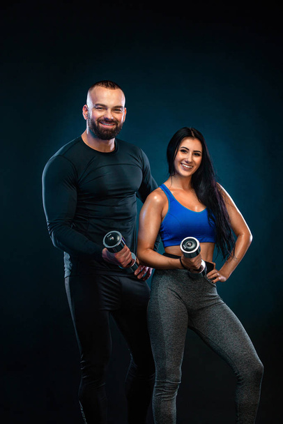 Muscular young fitness sports athlete in compression garment. Workout in gym with trainer. Man coach with woman ward. Girl with dumbbells. - Foto, Imagen