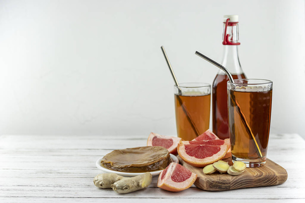 Kombucha superalimento pro biótico bebida de hongos de té en vasos y botella con pomelo, jengibre sobre fondo de madera blanca. espacio de copia
 - Foto, imagen