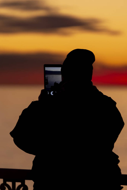 людина в капелюсі приймає пік заходу сонця на планшеті
 - Фото, зображення