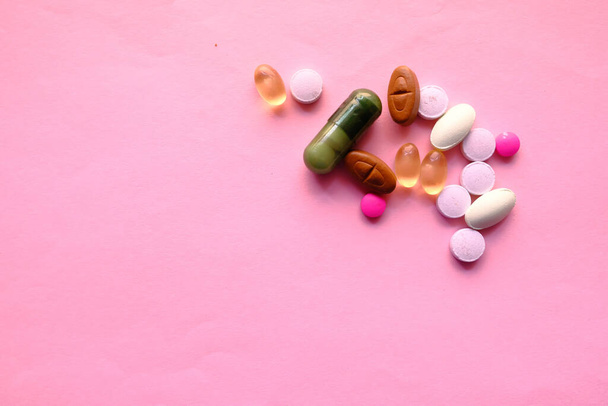 primo piano di pillole colorate versando su sfondo rosa  - Foto, immagini
