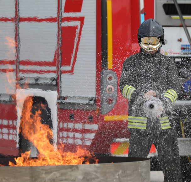 brave fireman with helmet during the extinguishing of a fire during the practical training test - Photo, Image