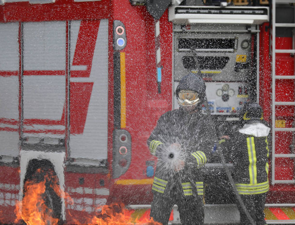 coraggioso vigile del fuoco con casco durante l'estinzione di un incendio durante la pratica nella stazione dei pompieri
 - Foto, immagini