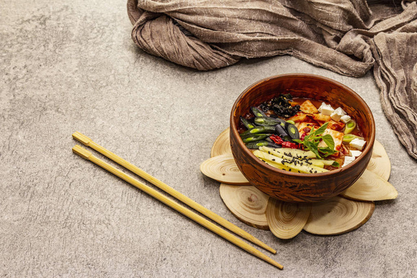 Traditional Korean spicy soup with kimchi, tofu, vegetables. Hot dish for healthy meal. Stone concrete background, copy space - Photo, Image