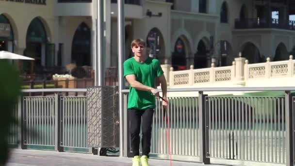 Man jumping with jump rope on the cityscape background of Dubai. Slow motion - Záběry, video