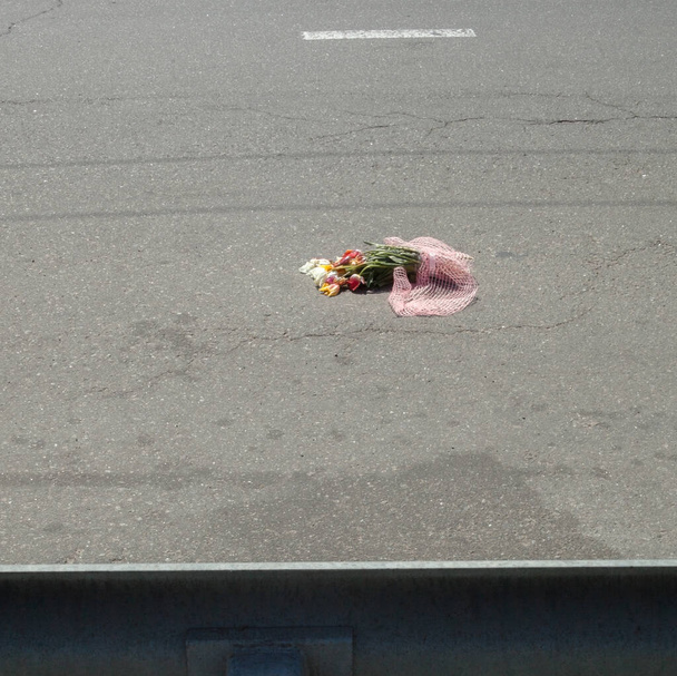 Buquê de flores na estrada. Flores na superfície do asfalto
. - Foto, Imagem