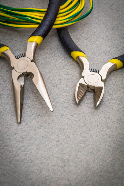 Kaksi pihdit työkalu ja johdot sähköasentaja harmaalla pohjalla käytetään päällikön korjata sähköä
 - Valokuva, kuva