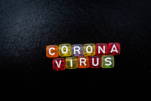 Colorful word CORONA VIRUS english alphabet cube on black color background , selective focus - Valokuva, kuva