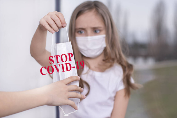 Személyi védőfelszerelés szükséges.Coronavirus.Egy kislány ül az ablaknál egy védő maszk, felajánlja, hogy egy védő maszkot az emberek, és megvédi magát a vírustól. - Fotó, kép