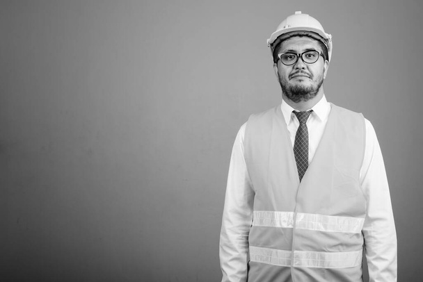 Estudio de hombre persa barbudo trabajador de la construcción contra fondo gris en blanco y negro - Foto, Imagen