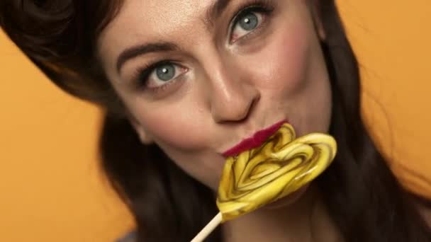 close-up uitzicht van pin-up vrouw likken lolly en knipogen met glimlach - Video