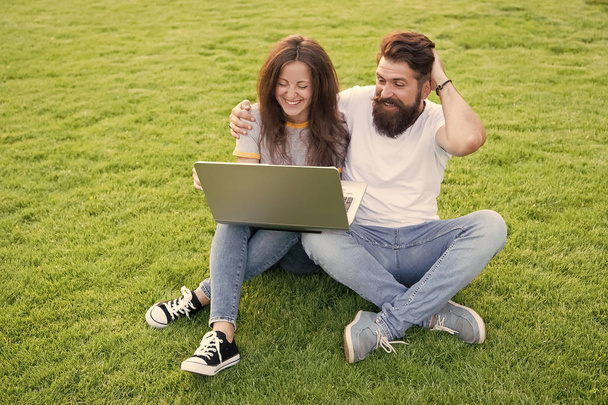 Modern technologies. Online work. Couple students green meadow. Laptop online communications. Surfing internet. Happy couple spend leisure outdoors with laptop. Man and girl looking laptop screen - Zdjęcie, obraz