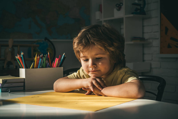 Cute pupil with funny face schooling work. Cute child boy in classroom near blackboard desk. Happy school kids at lesson. - Fotoğraf, Görsel