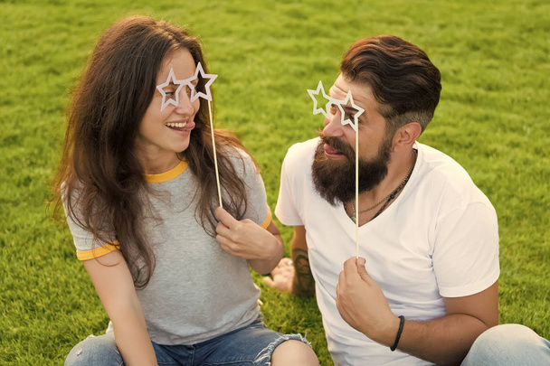 Couple in love cheerful youth booth props. Man bearded hipster and pretty woman cheerful faces. Youth day. Summer entertainment. Emotional people. Couple dating. Carefree couple having fun green lawn - Photo, Image