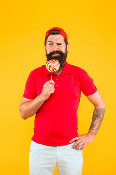 Funny man licking lollipop. Bearded man with lollipop. candy shop assistant. sweet and confectionary. Lollipop fun. Lick it. express positive emotions. sweet tooth happiness - Φωτογραφία, εικόνα