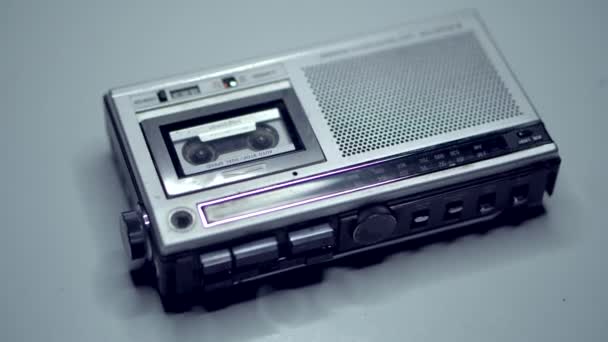 An audio cassette recorder created in 90s lies on a white plastic tabletop. Record sound on magnetic tape. Dictaphone. Vintage. Professional journalist tool. - Footage, Video
