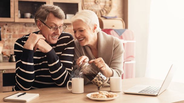 Feliz pareja de ancianos tomando café, relajarse juntos en la cocina
 - Foto, imagen