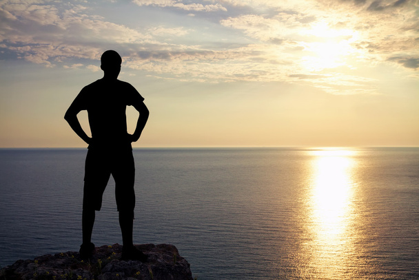 Silhouette dell'uomo sulla roccia al tramonto. L'uomo in cima alla montagna
. - Foto, immagini