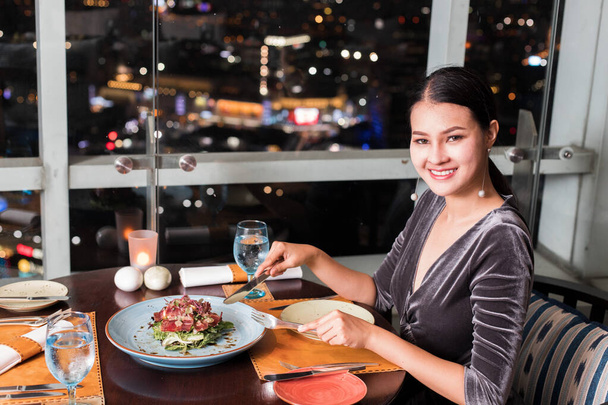 アジアの美しい女性は秘密のレシピを持つ高級屋上レストランで夕食を持っていますスペイン料理のプレートコースセットのメニュー木製のテーブルの上に少し熱く、ユニークな味料理. - 写真・画像