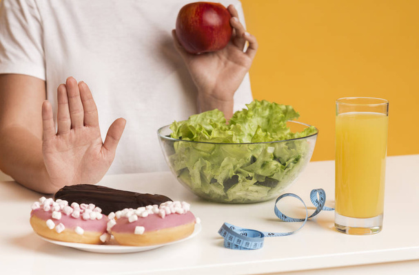 Unrecognizable woman rejecting junk food and choosing apple and salad instead - Foto, Imagem