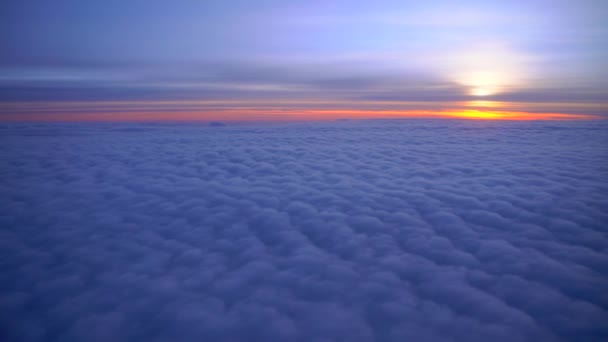 Repülni egy repülőn. Napkelte vagy naplemente egy repülőgép-megvilágítóból. Egy repülő szárny repül át a pamut felhők. A kilátás a repülő ablakából. Repülőgép. Utazzon repülővel. Színes ég. - Felvétel, videó