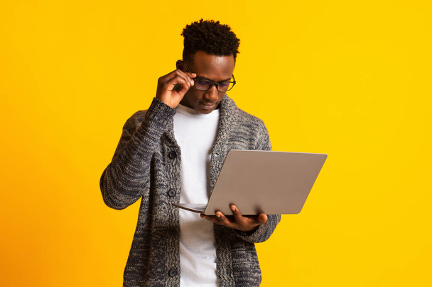 Pensativo chico africano joven freelancer mirando su computadora portátil
 - Foto, imagen
