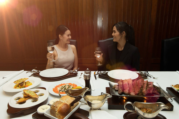 Couple of two 2 Asian Woman Black hair having Lunch Steak grill salmon bread Dinner of Western food in fusion restaurant cafe and eat alone. Concept enjoy eating tom boy best friends and serve each - Photo, Image