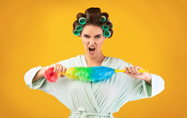Furious Housewife Shouting Holding Cleaning Feather Duster On Yellow Background - Foto, Imagem