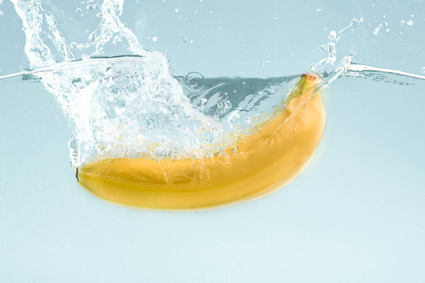 Makea banaani roiskuvassa vedessä sinisellä pohjalla
 - Valokuva, kuva