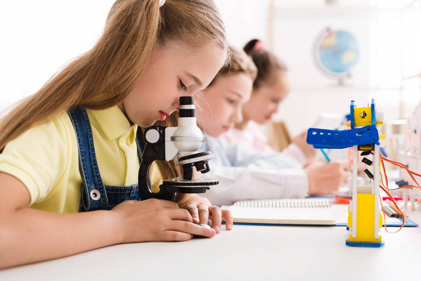 Schoolgirl looking at microscope at stem robotic class - Foto, Bild