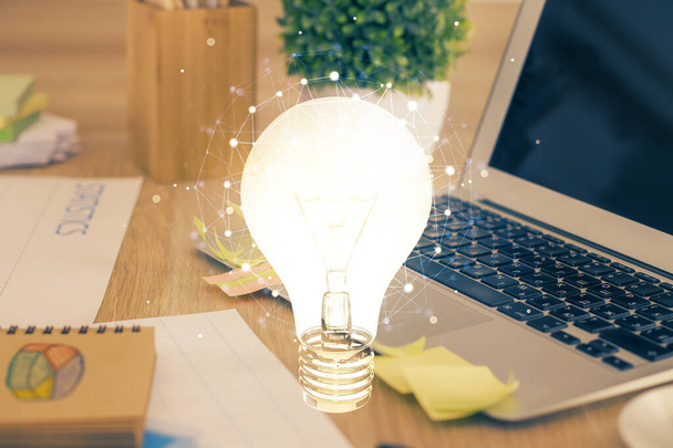 Computer on desktop in office with bulb icon hologram. Multi exposure. Concept of idea. - 写真・画像