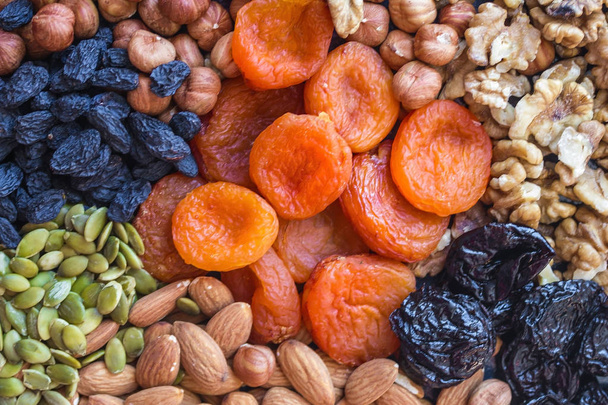 Dried apricots, raisins, almonds, hazelnuts, walnuts, prunes and pumpkin seeds. Bright, colorful background, natural shades. Organic food, vegetarian cuisine. - Photo, Image