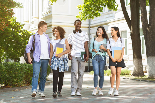 Estudantes universitários felizes andando juntos no campus, conversando e rindo ao ar livre
 - Foto, Imagem