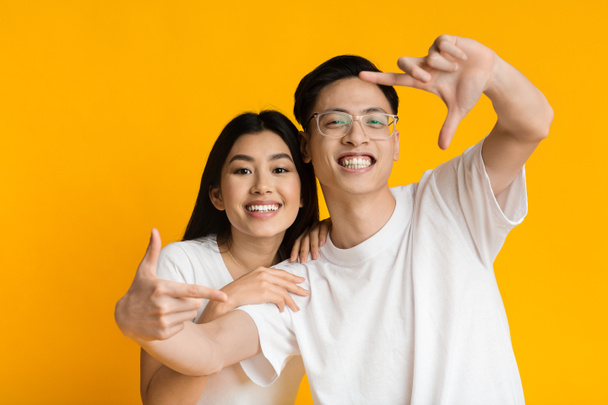 Giovane asiatico coppia mostrando telaio segno con dita
 - Foto, immagini