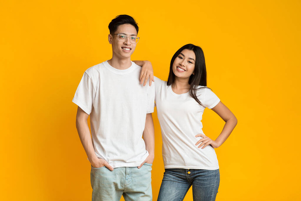 Asian couple in love posing over yellow background - Φωτογραφία, εικόνα