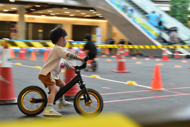 Kind spielt Laufrad auf Rennstrecke, Geschwindigkeit Bewegungsunschärfe Bild - Foto, Bild
