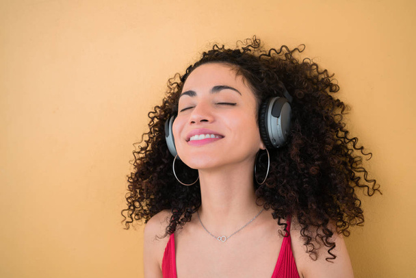 Portrait of young afro woman enjoying and listening to music with headphones. Technology and lifestyle concept. - Foto, afbeelding