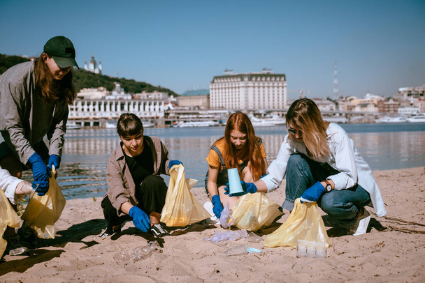 ビーチでプラスチック廃棄物を収集活動家の友人のグループ。環境保全. - 写真・画像